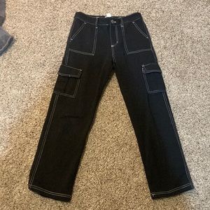 Black cotton cargo pants with white stitching.